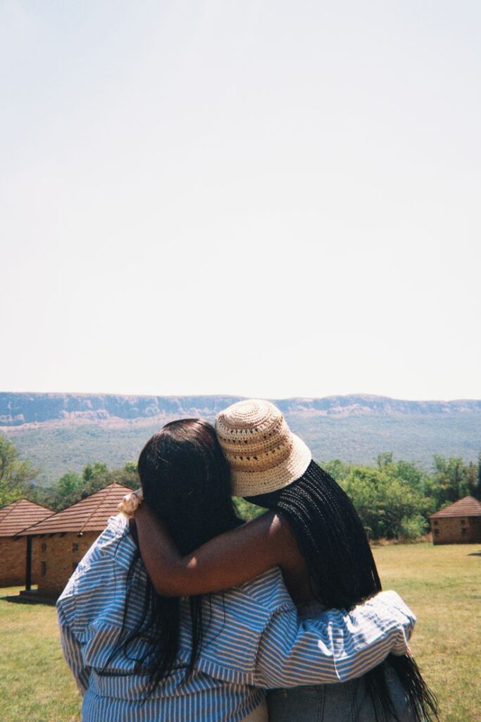 Two women hugging warmly while looking out at a scenic landscape