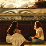 Two women sitting together at sunset having a warm and honest conversation