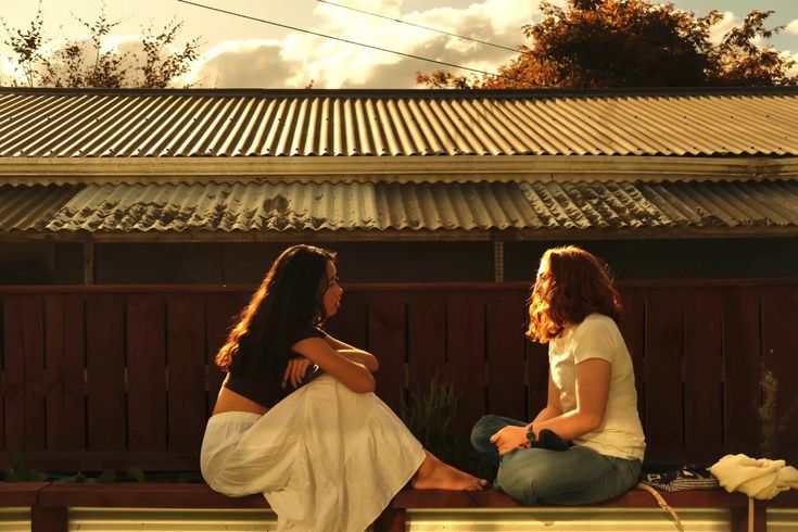Two women sitting together at sunset having a warm and honest conversation