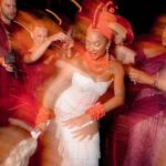 Nigerian bride in traditional coral beads and white dress dancing joyfully at her wedding