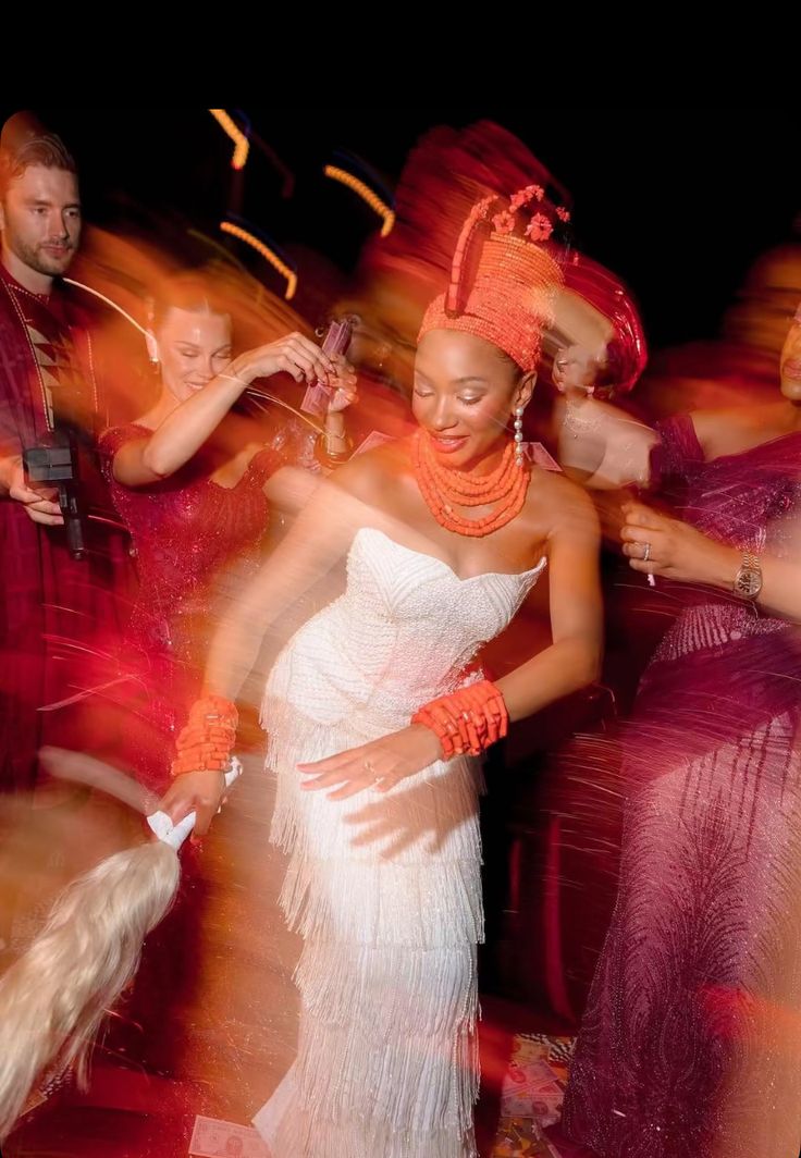 Nigerian bride in traditional coral beads and white dress dancing joyfully at her wedding